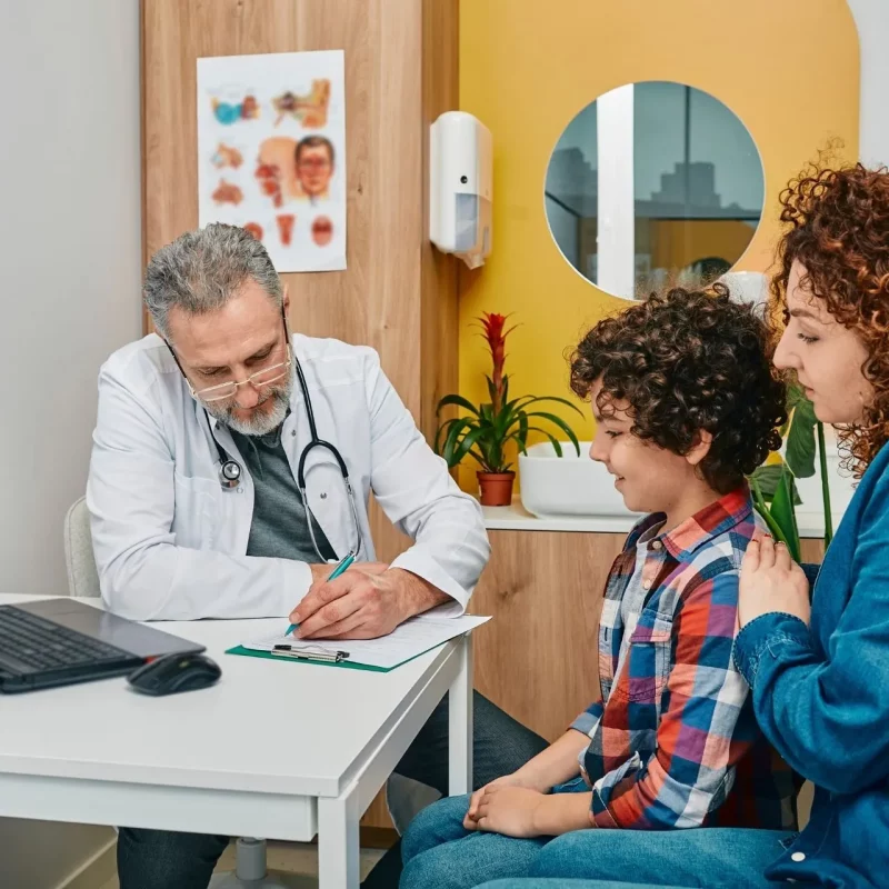A doctor in consultation with a child and their parent at Ayr Medical Group